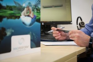 Im Vordergrund Key-Visual der Innoperform, im Hintergrund Hand, die einen arimeo Fensterfalzlüfter in der Hand hält