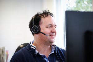 Technischer Berater sitzt mit Headset vor dem Computerbildschirm